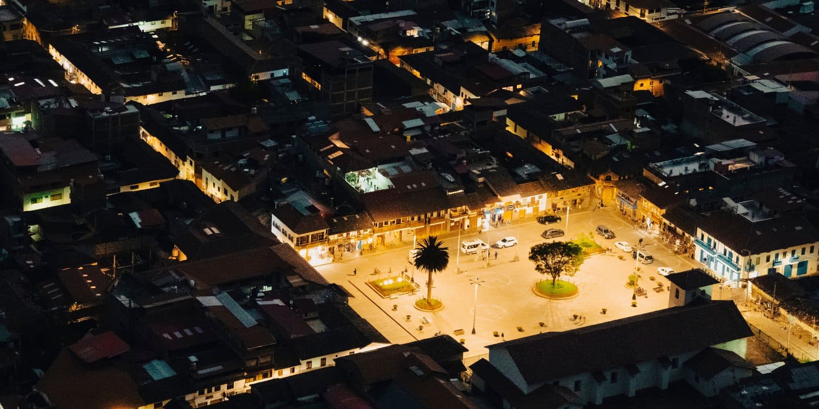 Pisac's plaza at night, lit windows under the dark hills of the Sacred Valley